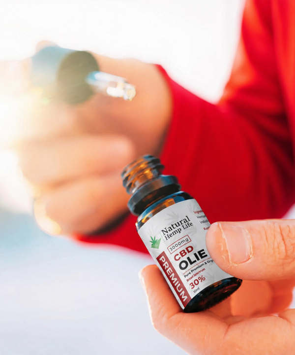 Sløret nærbillede af en person i rød trøje, der holder en pipette med CBD Olie 30%